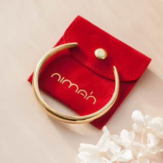 Arabic bracelet in gold bangle design lay on Nimah London jewellery pouch