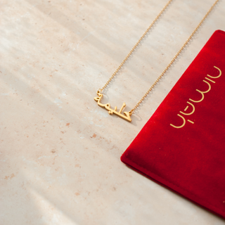 image of the arabic name necklace next to red pouch